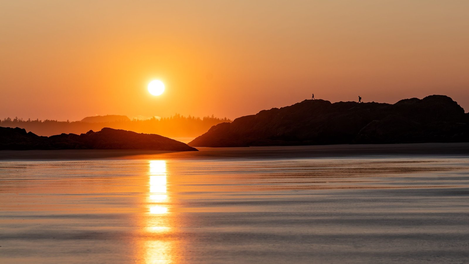 Gorgeous sunset reflecting over calm waters with silhouettes, capturing the serene beauty of British Columbia.