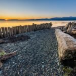 Stunning sunset over Comox Beach with wooden logs and a serene ocean view.